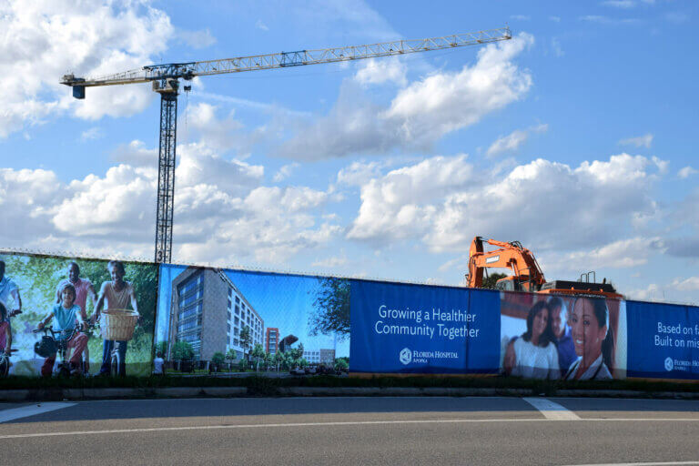 Blue commercial industrial windscreen for Florida Hospital construction with white branding