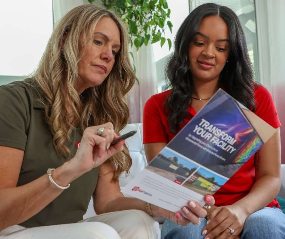 Two women looking over a brochure from Ball Fabrics.